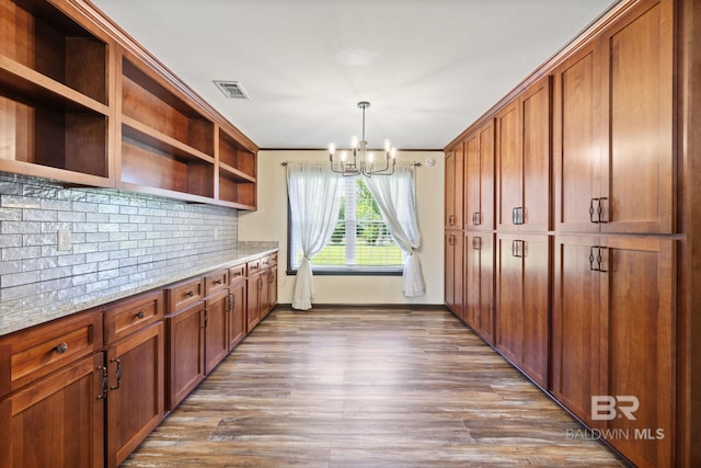 kitchen with light stone counters, decorative light fixtures, dark wood-type flooring, a notable chandelier, and decorative backsplash