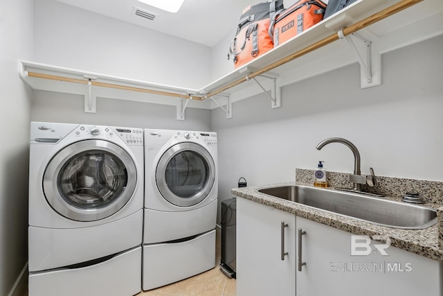clothes washing area with a sink, visible vents, cabinet space, and washer and dryer