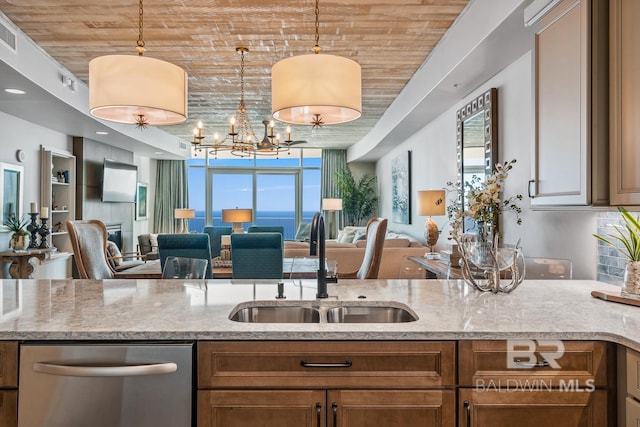 kitchen featuring a sink, decorative light fixtures, light stone counters, open floor plan, and dishwasher