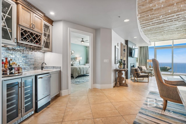 bar featuring a sink, tasteful backsplash, wine cooler, light tile patterned floors, and wet bar