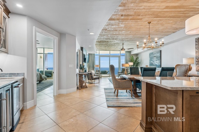 kitchen featuring light tile patterned floors, light stone countertops, a sink, open floor plan, and a chandelier