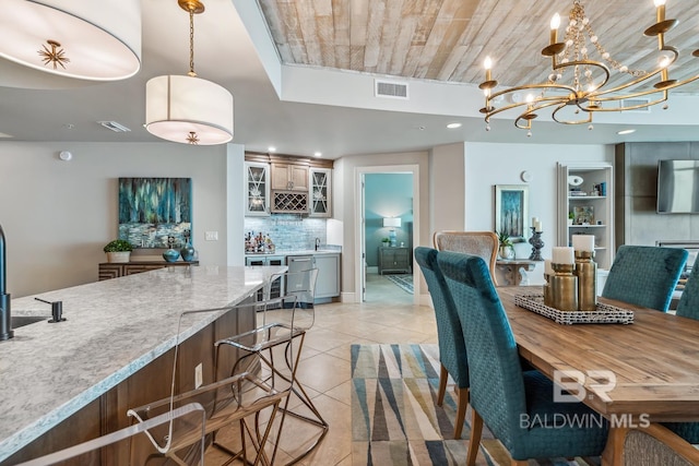 dining space featuring indoor wet bar, a notable chandelier, light tile patterned floors, and visible vents