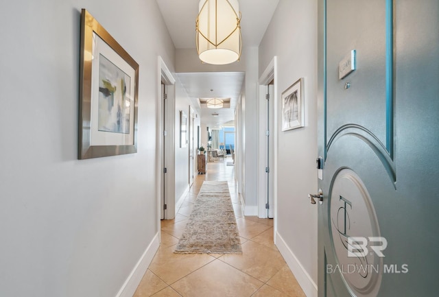 hallway featuring light tile patterned floors and baseboards