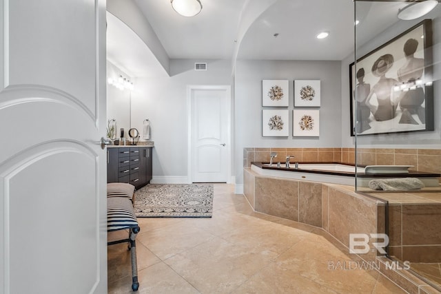bathroom with visible vents, tile patterned floors, baseboards, a bath, and vanity