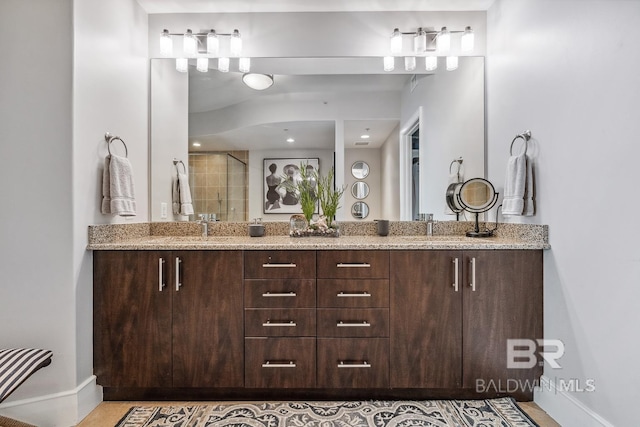 full bathroom featuring a sink, a stall shower, baseboards, and double vanity