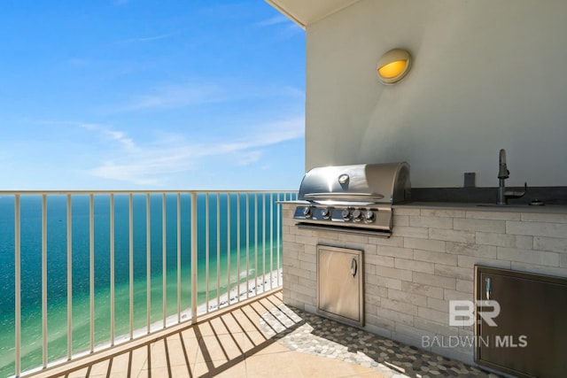 view of patio with grilling area, a water view, a balcony, and an outdoor kitchen