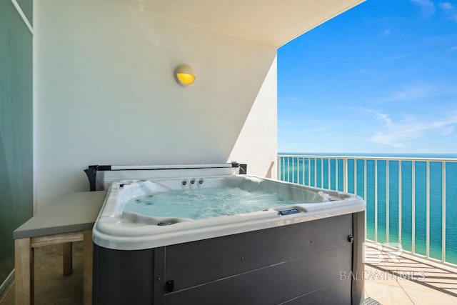 balcony featuring a water view and a hot tub