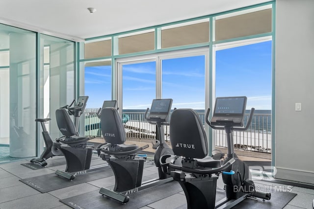 exercise room with floor to ceiling windows and baseboards