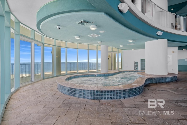 pool featuring an indoor hot tub and a water view
