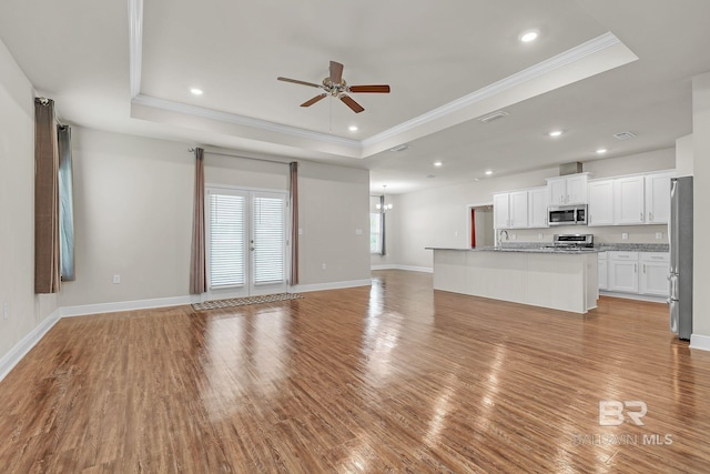 24774 Smarty Jones Cir, Daphne, AL 36526 - unfurnished living room featuring a raised ceiling, crown molding, a ceiling fan, light wood-type flooring, and baseboards