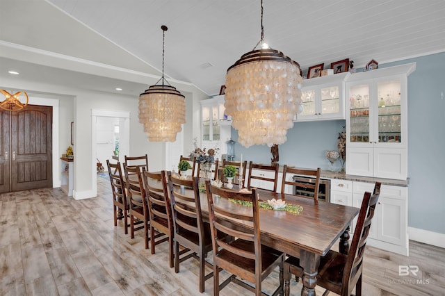 dining space with vaulted ceiling, light wood-type flooring, and an inviting chandelier