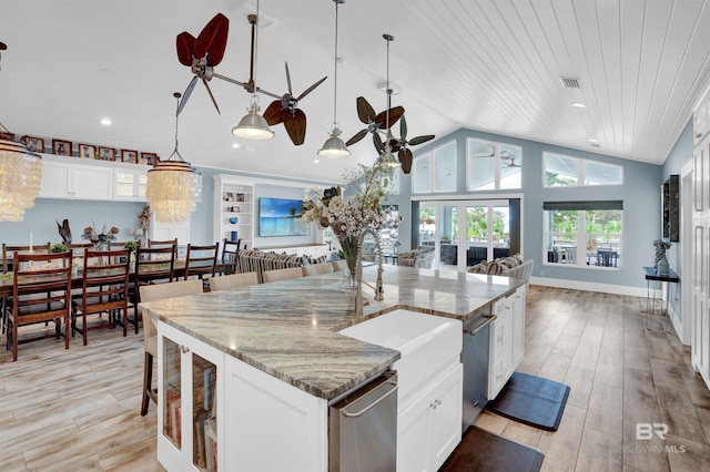 kitchen featuring lofted ceiling, light stone counters, and decorative light fixtures