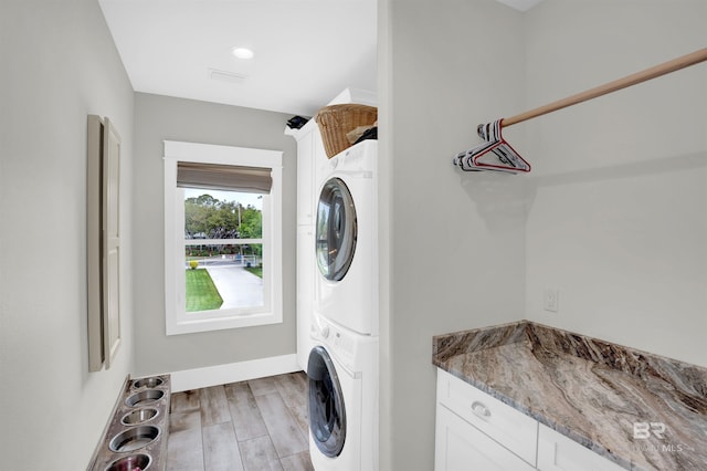 washroom with light hardwood / wood-style flooring and stacked washing maching and dryer