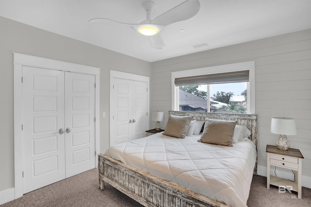 carpeted bedroom featuring ceiling fan and two closets