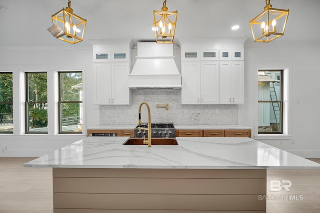 kitchen with white cabinetry, custom range hood, and decorative light fixtures