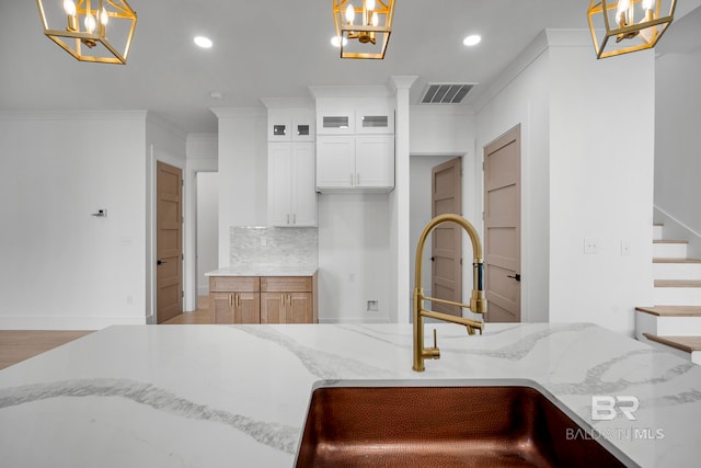 kitchen featuring white cabinetry, light hardwood / wood-style floors, sink, and pendant lighting