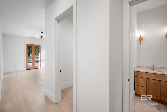 corridor with french doors, light hardwood / wood-style flooring, and sink