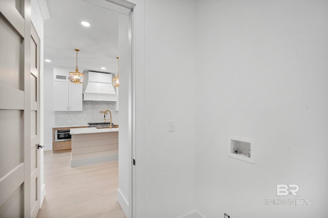 laundry room featuring sink, light hardwood / wood-style flooring, and hookup for a washing machine