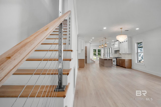 staircase with sink, a chandelier, and wood-type flooring