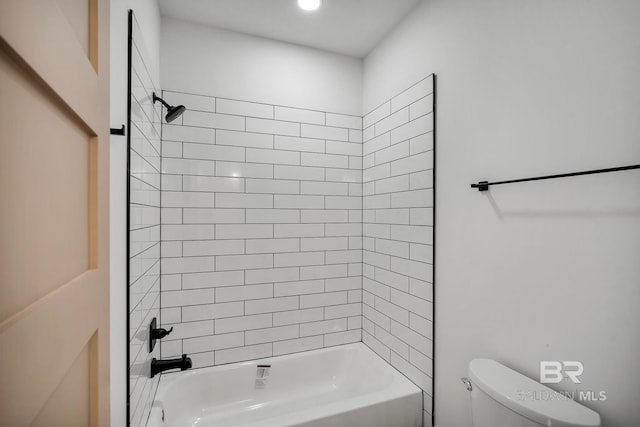 bathroom with toilet and tiled shower / bath