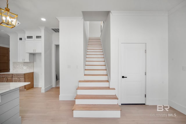 stairs featuring hardwood / wood-style flooring and ornamental molding