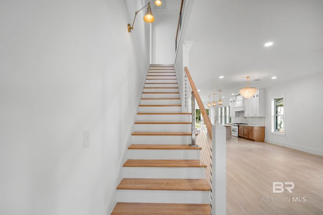 stairway with hardwood / wood-style flooring and an inviting chandelier