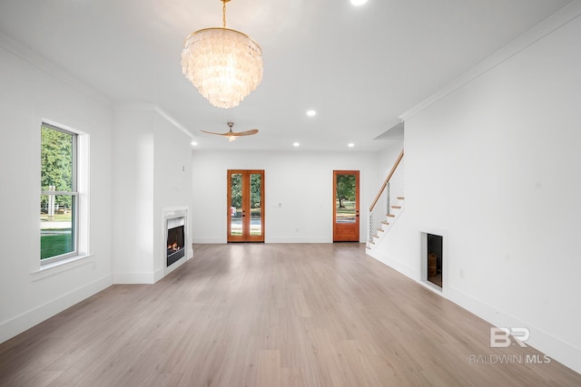 unfurnished living room featuring light hardwood / wood-style floors, crown molding, and ceiling fan with notable chandelier