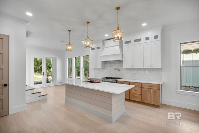 kitchen featuring a center island, custom exhaust hood, decorative light fixtures, and white cabinets