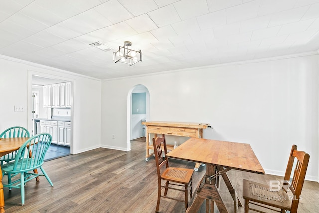 dining space featuring dark wood-type flooring and crown molding