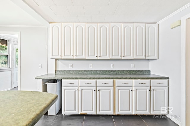 kitchen featuring white cabinetry, ornamental molding, and dark tile patterned floors