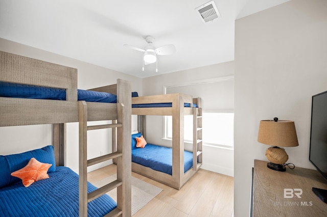 bedroom with ceiling fan, wood finished floors, and visible vents