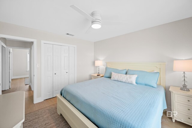 bedroom featuring light wood finished floors, ceiling fan, visible vents, and a closet