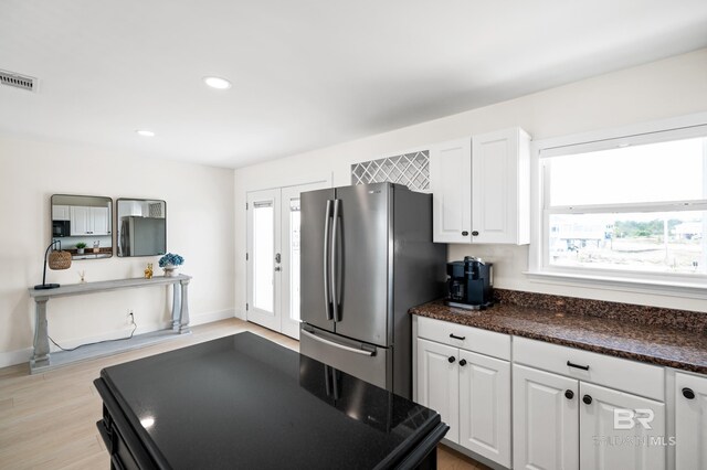 kitchen with a healthy amount of sunlight, white cabinetry, visible vents, and freestanding refrigerator