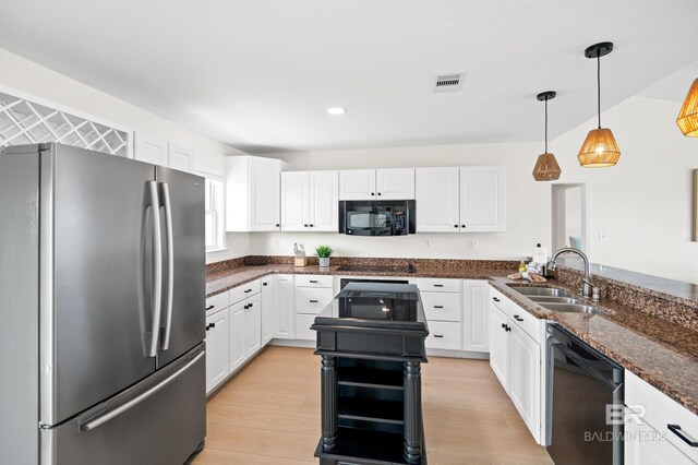 kitchen featuring visible vents, dishwashing machine, freestanding refrigerator, black microwave, and a sink