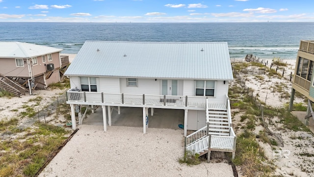 exterior space featuring a water view, metal roof, a carport, driveway, and stairs