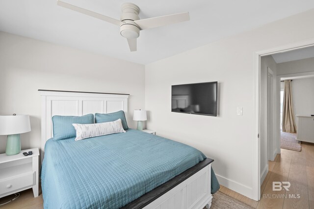 bedroom with a ceiling fan, light wood-style flooring, and baseboards