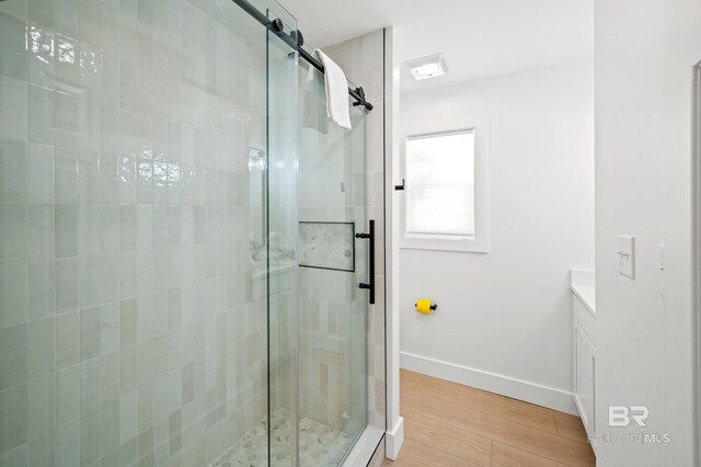 bathroom with a stall shower, baseboards, wood finished floors, and vanity