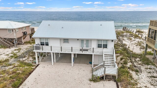 exterior space with driveway, stairway, metal roof, a water view, and a carport