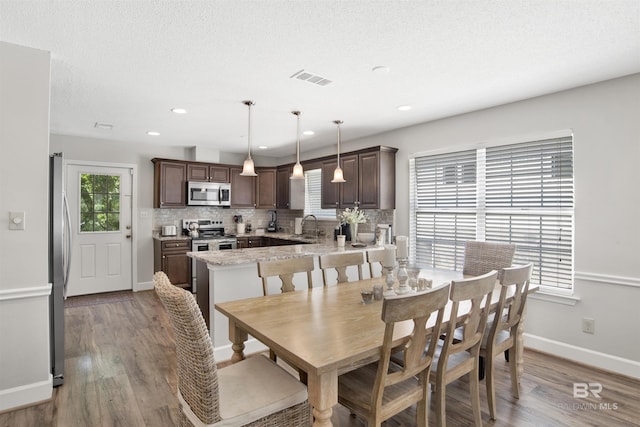 dining space featuring sink, a textured ceiling, and light wood-type flooring