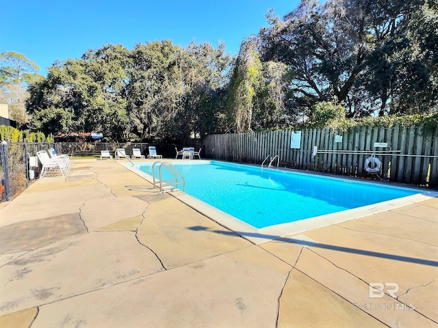 community pool with a patio area and fence