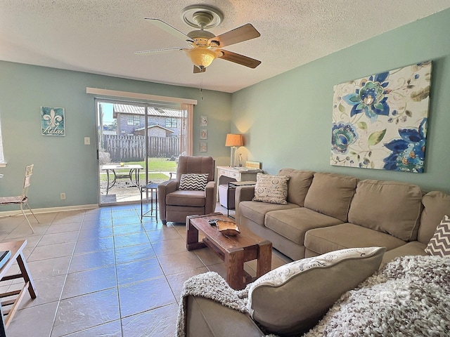 living room featuring baseboards, a ceiling fan, a textured ceiling, and light tile patterned flooring