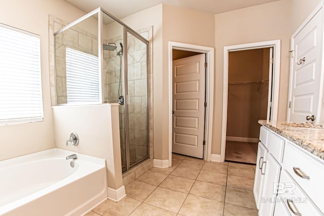 bathroom featuring vanity, a spacious closet, a shower stall, a bath, and tile patterned floors