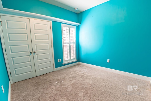 unfurnished bedroom featuring a closet, light colored carpet, and baseboards