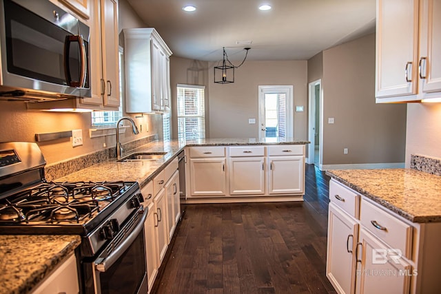 kitchen featuring light stone counters, dark wood-type flooring, a peninsula, stainless steel appliances, and white cabinetry