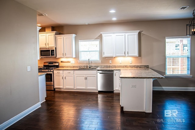 kitchen featuring stainless steel appliances, light stone counters, a sink, and white cabinets