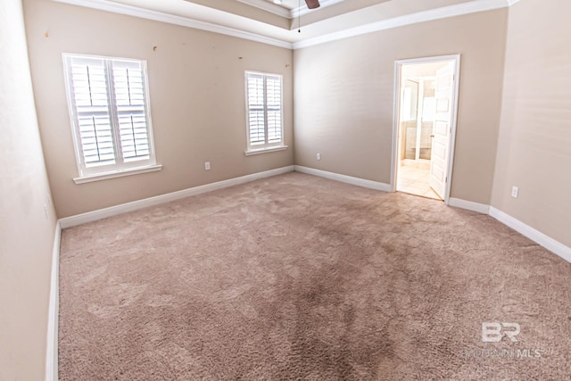 carpeted spare room with crown molding, baseboards, and ceiling fan