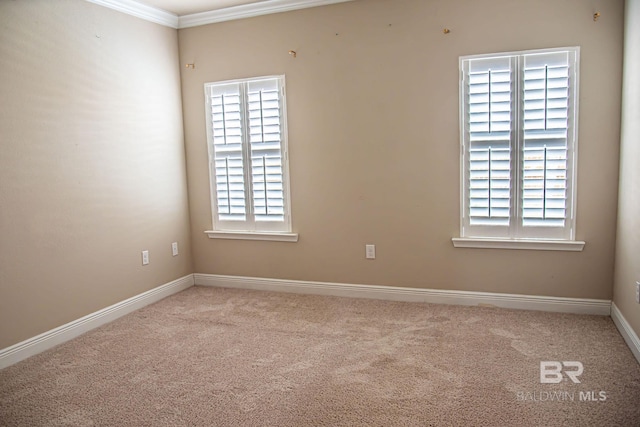 spare room with light carpet, baseboards, and crown molding