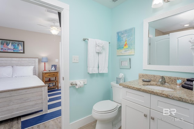 bathroom featuring toilet, vanity, a ceiling fan, wood finished floors, and baseboards