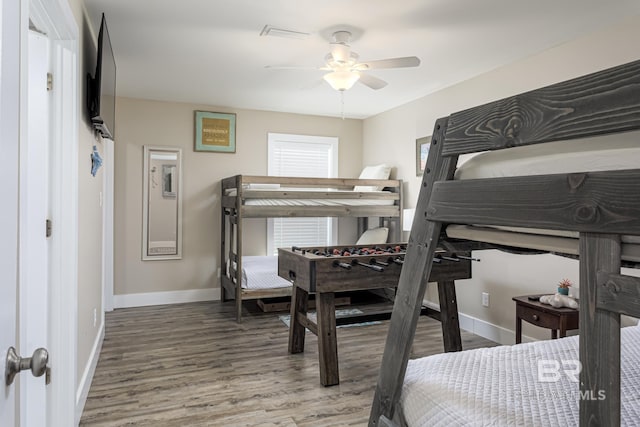 bedroom featuring baseboards, wood finished floors, and a ceiling fan