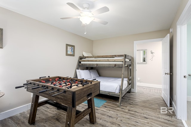 bedroom featuring baseboards, wood finished floors, and a ceiling fan